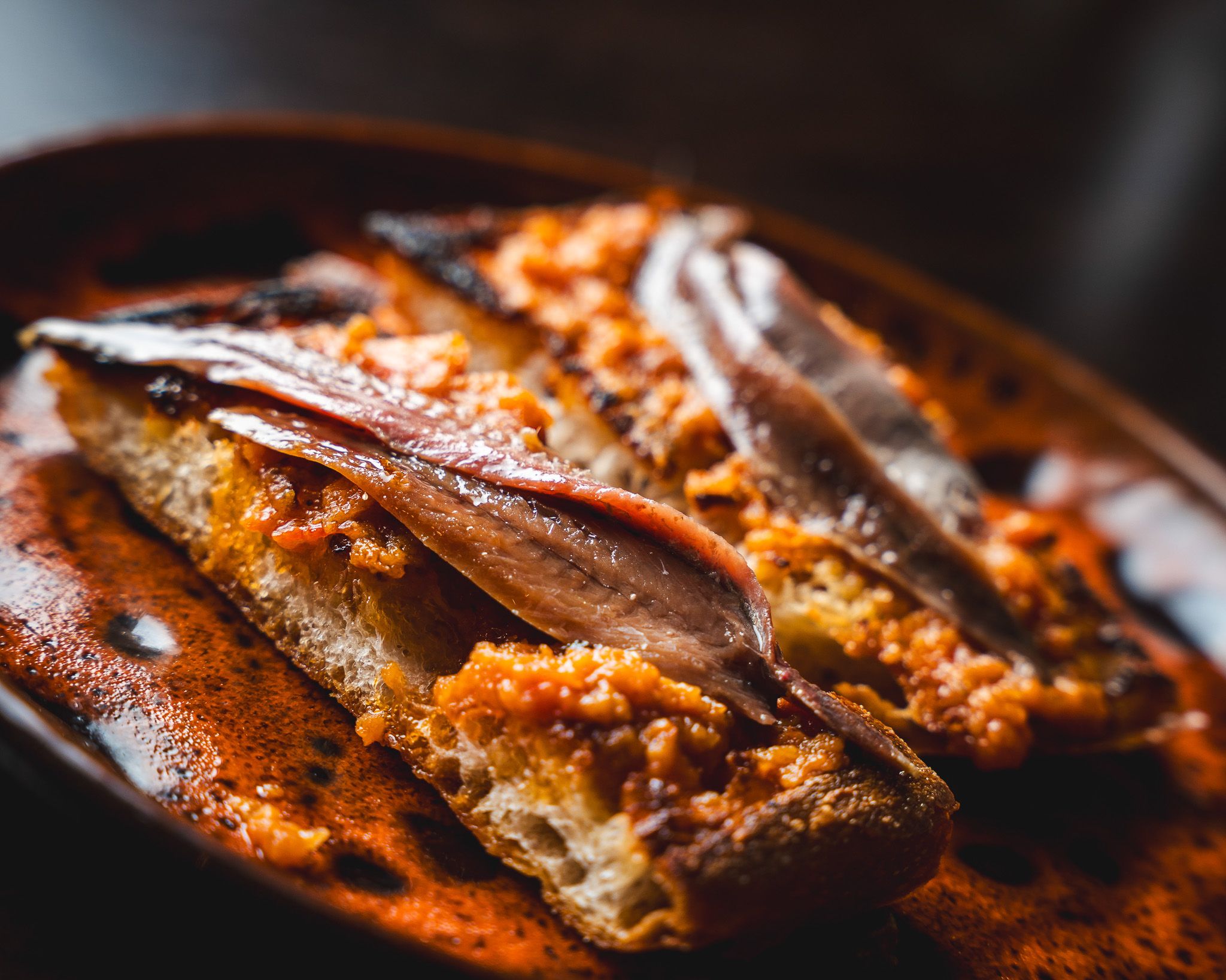 Anchovy toast finished with herbs and olive oil