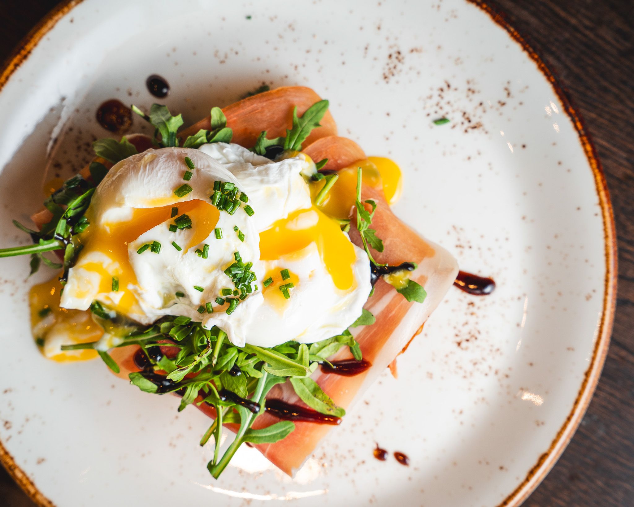 Soft eggs and prosciutto on toasted bread