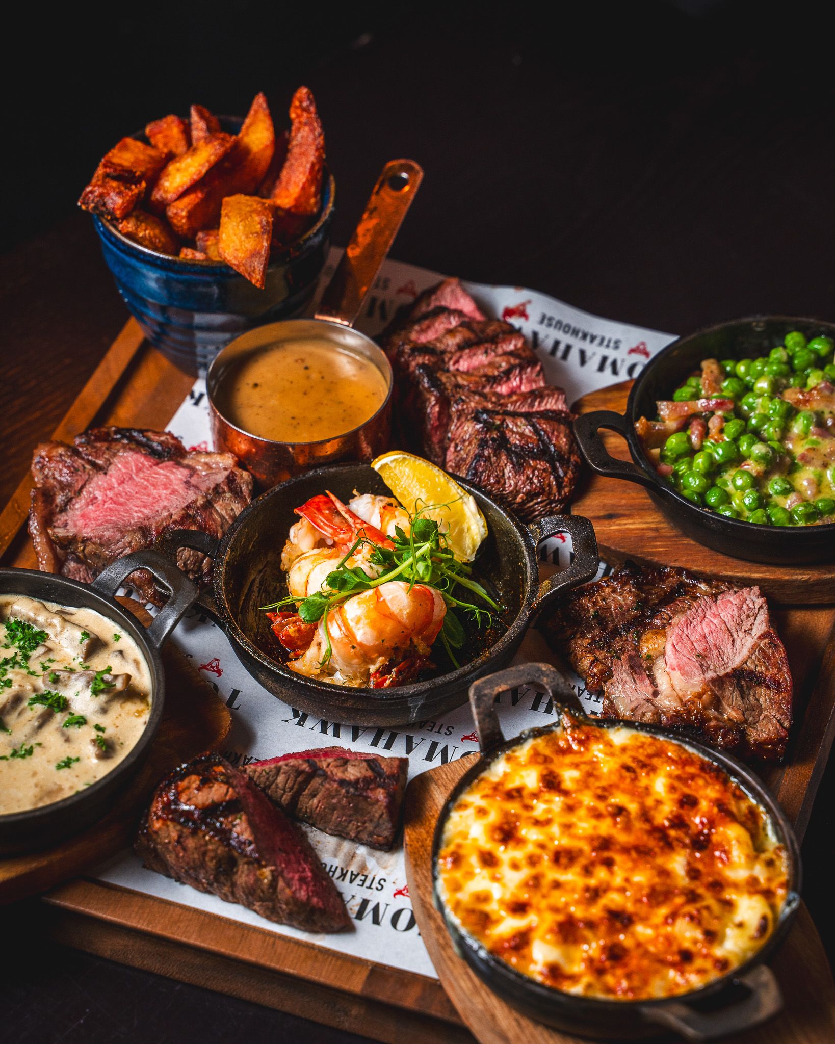 A Tomahawk sharing board of sliced steaks, garlic butter prawns and sides